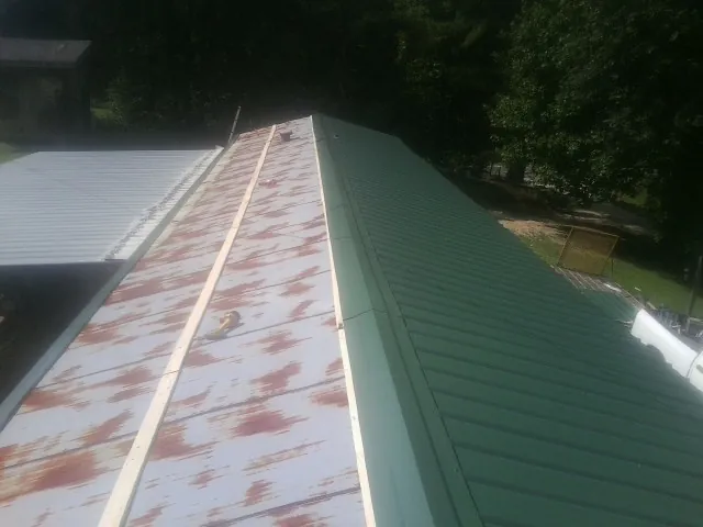 Old rusted panels beside newly installed green metal roofing — Wind Damage Roof Repair by Roofing Brothers in High Bridge