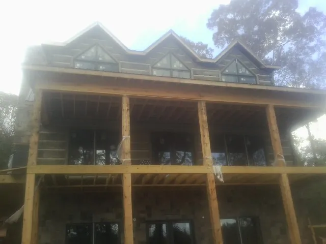 Dormers and porch framing on a large log home under construction — Roof Coating work by our crew in High Bridge