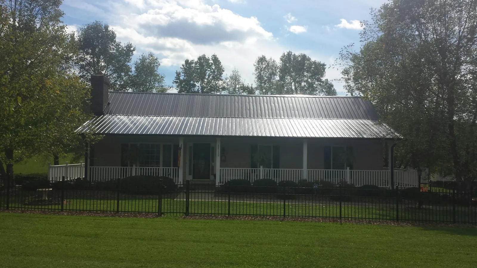 Gray metal roof on a brick ranch with a full width front porch — Gutter Guard Installation work by our crew in High Bridge