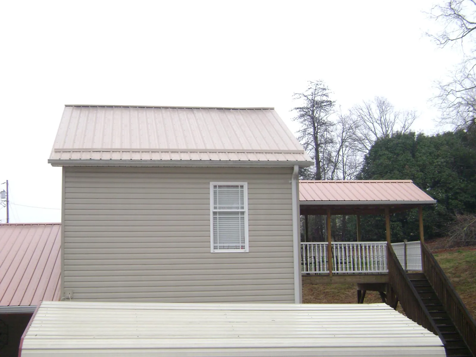 Tan metal roofs on a two story addition and attached porch, from a Roof Replacement job in High Bridge